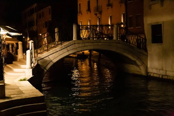 Puente sobre el canal cerca de edificios antiguos por la noche en Venecia, Italia - foto de stock