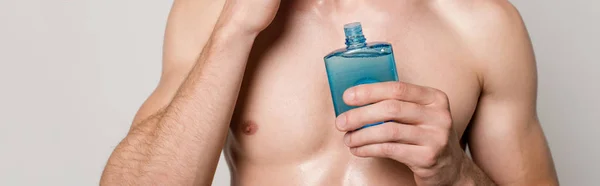 Cropped view of sexy man with muscular torso with after shave lotion isolated on grey, panoramic shot — Stock Photo