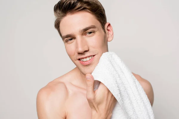 Sonriente hombre sexy con torso muscular sosteniendo toalla de algodón aislado en gris - foto de stock