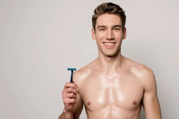 Smiling sexy man with muscular torso holding shaver isolated on grey — Stock Photo