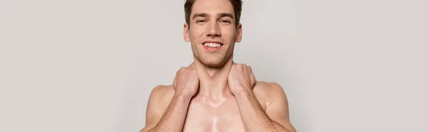 Sonriente sexy hombre con torso muscular posando aislado en gris, tiro panorámico - foto de stock