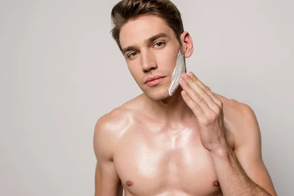 Sexy hombre con torso muscular aplicación de espuma de afeitar aislado en gris - foto de stock