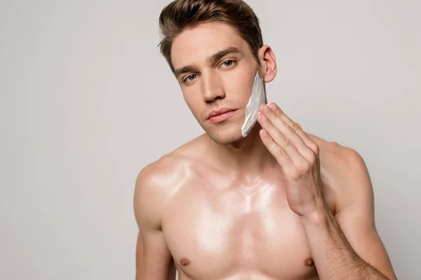 Homme sexy avec torse musculaire appliquant mousse à raser isolé sur gris — Photo de stock