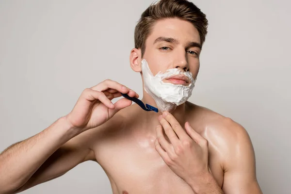 Sexy man with muscular torso shaving isolated on grey — Stock Photo