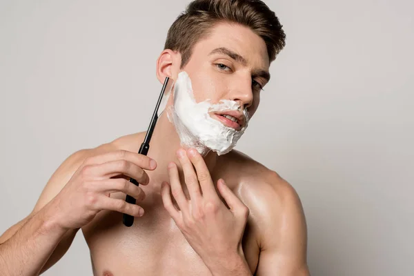 Sexy man with muscular torso shaving with straight razor isolated on grey — Stock Photo