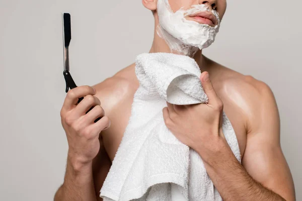 Abgeschnittene Ansicht von sexy Mann mit muskulösem Oberkörper und Rasierschaum im Gesicht hält Rasiermesser und Handtuch isoliert auf grau — Stockfoto