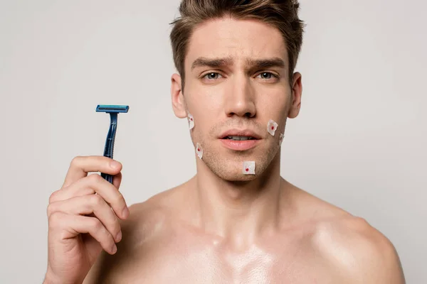 Homme sexy avec le torse musculaire et les blessures sanglantes après le rasage tenant rasoir isolé sur gris — Photo de stock