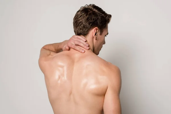 Вид ззаду людини, що має біль в шиї ізольовано на сірому — стокове фото