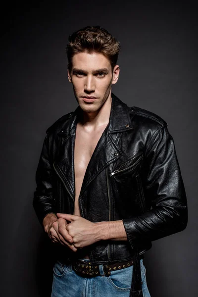 Сексуальний молодий чоловік з м'язистим торсом в куртці і джинсах на чорному тлі — стокове фото