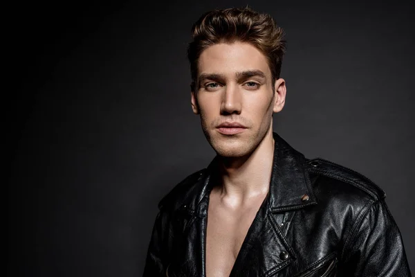 Sexy young man in biker jacket on black background — Stock Photo