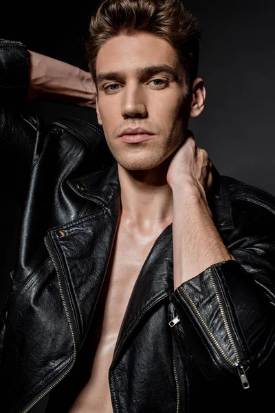 Sexy young man in biker jacket posing on black background — Stock Photo