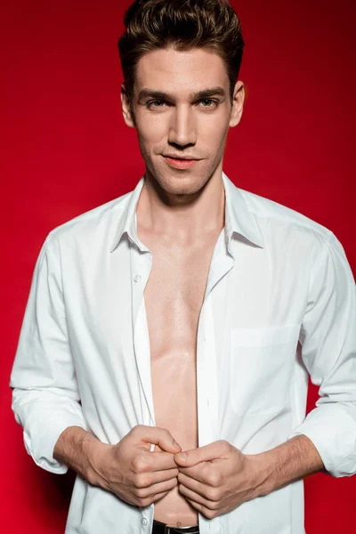 Sexy jovem elegante homem em camisa desabotoada no fundo vermelho — Fotografia de Stock