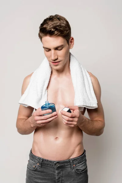 Sexy man with muscular torso with after shave lotion and towel isolated on grey — Stock Photo