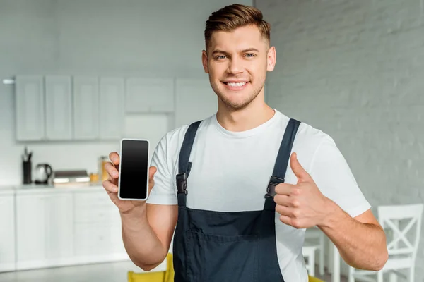 Feliz instalador segurando smartphone com tela em branco e mostrando polegar para cima — Fotografia de Stock