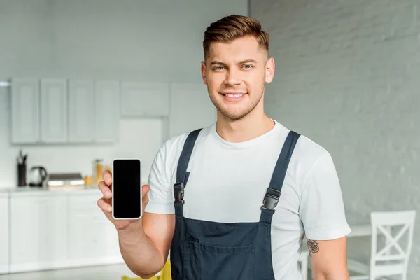 Happy installer holding smartphone with blank screen and looking at camera — Stock Photo