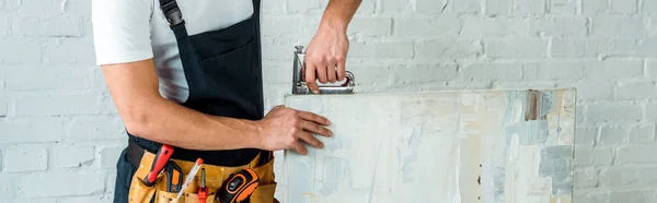 Tiro panorâmico do instalador segurando grampeador de construção perto da pintura — Fotografia de Stock