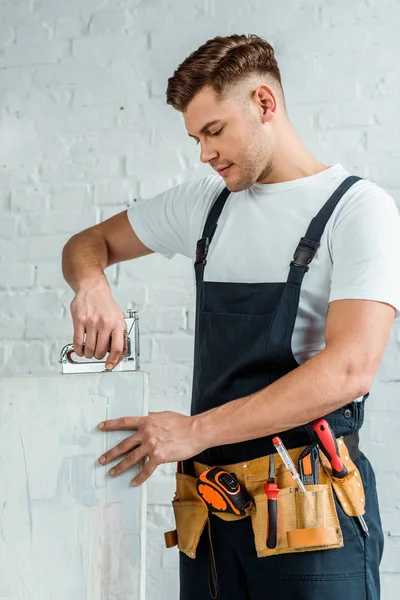 Красивый монтажник держит строительный степлер возле покраски — стоковое фото