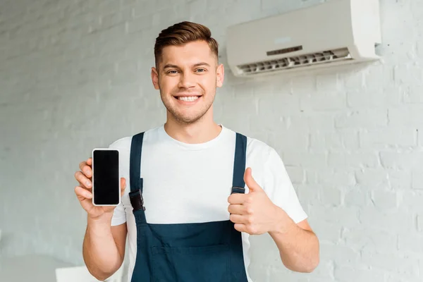 Fröhlicher Installer zeigt Daumen hoch, während er Smartphone mit leerem Bildschirm hält — Stockfoto