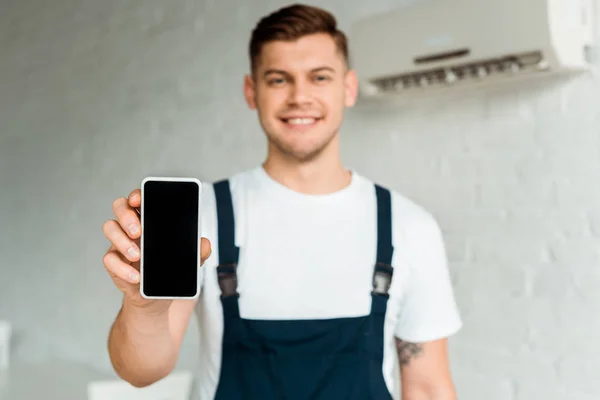 Foco seletivo do smartphone com tela em branco na mão do instalador feliz — Fotografia de Stock