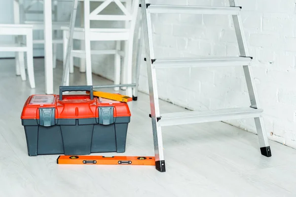 Caja de herramientas naranja cerca de escalera metálica - foto de stock