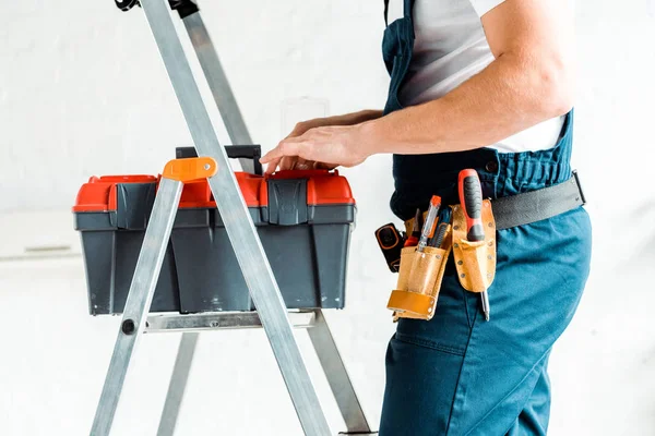 Cropped view of installer standing on ladder and holding tool box — Stock Photo