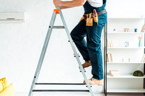 Cropped view of installer in overalls climbing ladder — Stock Photo