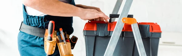 Panoramic shot of installer standing on ladder and holding tool box — Stock Photo