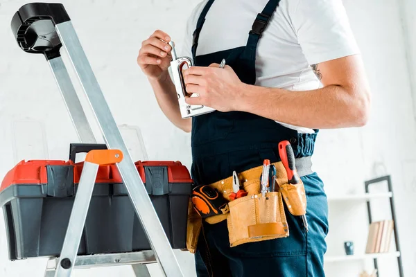 Cropped view of installer with tool belt holding construction stapler — Stock Photo