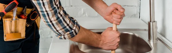 Panoramic shot of plumber holding plunger near sink in kitchen — Stock Photo