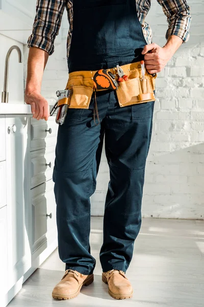 Cropped view of installer with tool belt standing with clenched fist — Stock Photo