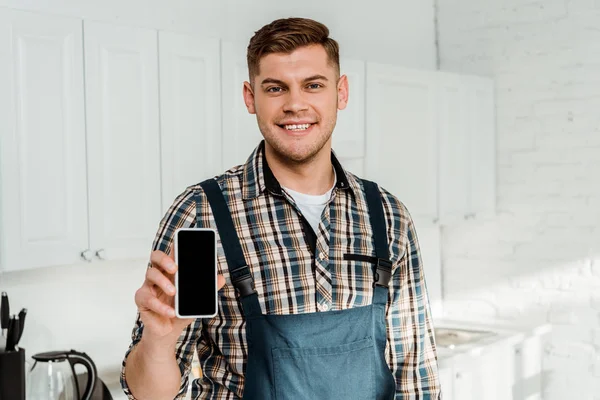 Fröhlicher Installateur hält Smartphone mit leerem Bildschirm — Stockfoto