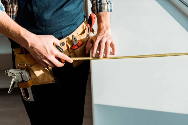 Cropped view of installer measuring windowsill while holding measuring tape — Stock Photo