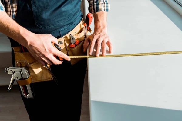 Vista ritagliata del davanzale dell'installatore di misurazione tenendo premuto il nastro di misurazione — Stock Photo