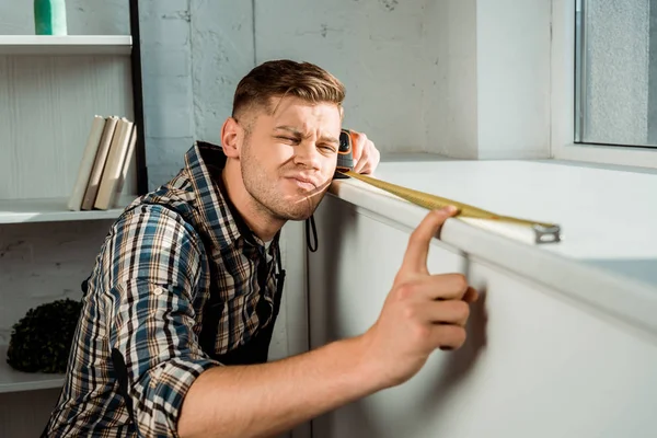 Selective focus of focused installer measuring windowsill while holding measuring tape — Stock Photo