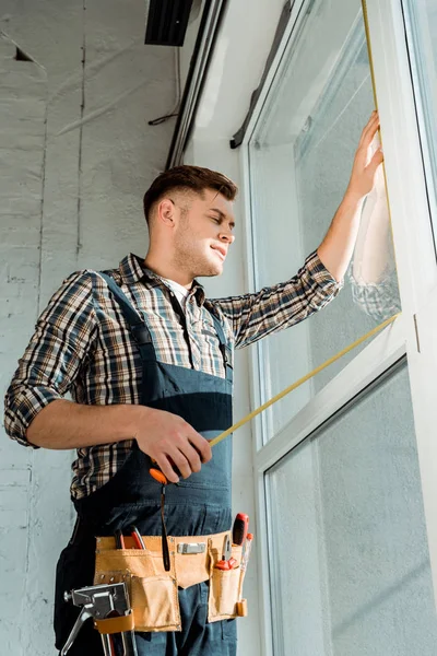 Installer standing near windows and holding measuring tape — Stock Photo