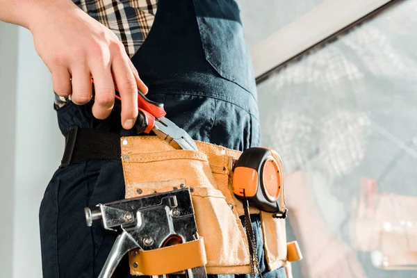 Ausgeschnittene Ansicht des Installateurs in Werkzeugband, der eine Zange nimmt — Stockfoto