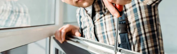 Panoramic shot of installer holding screwdriver near window — Stock Photo