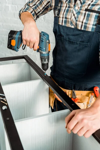 Cropped view of installer holding hammer drill while installing rack — Stock Photo