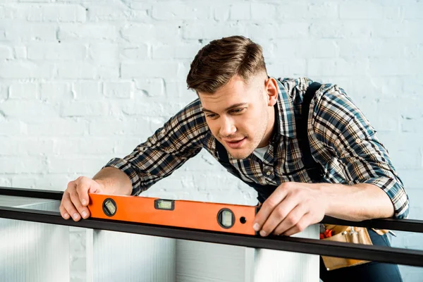 Installateur hält Gebäudeebene mit Messgestell — Stockfoto