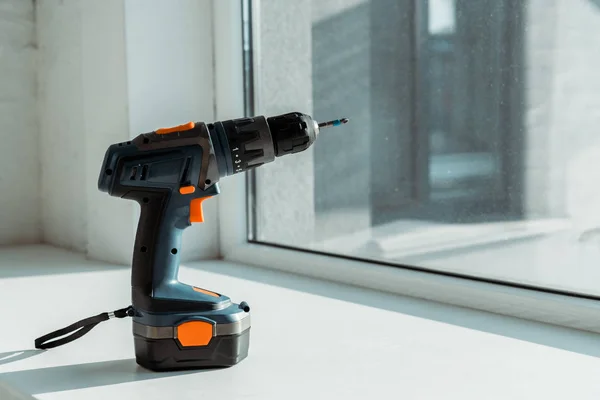 Hammer drill on white windowsill near window — Stock Photo