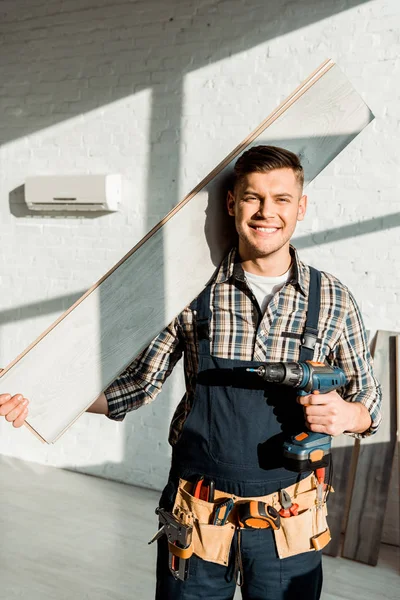 Installateur joyeux tenant étagère et perceuse à marteau — Photo de stock