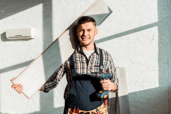 Installateur souriant tenant étagère et perceuse à marteau — Photo de stock