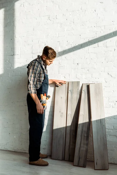 Handsome installer standing near wooden shelves — Stock Photo