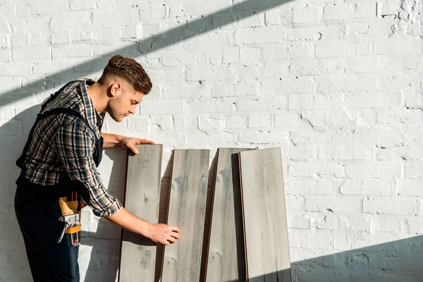 Seitenansicht eines stattlichen Installateurs, der neben Holzregalen steht — Stockfoto