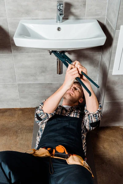Fokussierter Installateur hält Gleitfugenzange in der Nähe von Rohr im Bad — Stockfoto