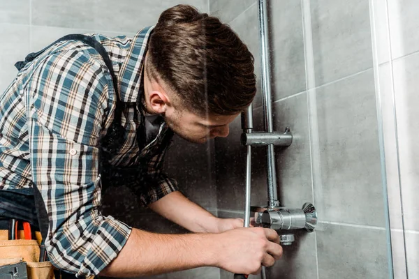 Installateur berührt Metallrohr im Badezimmer — Stockfoto