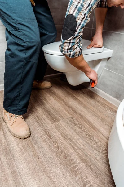 Vista recortada del hombre la instalación de inodoro blanco - foto de stock