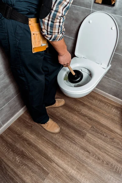 Vue recadrée du piston de maintien du plombier près des toilettes blanches — Photo de stock