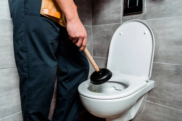 Cropped view of plumber holding plunger near toilet — Stock Photo