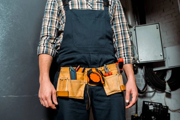 Vista recortada del instalador en overoles con cinturón de herramientas naranja - foto de stock